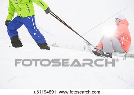 Low section of man giving sled ride to woman in snow View Large Photo Image Stock Image - Low section of man giving sled ride to woman in snow. Fotosearch