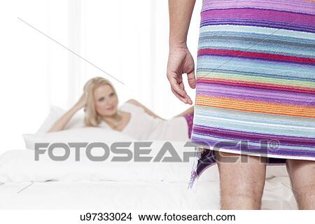 Low section of man wrapped in towel with woman in background at hotel room View Large Photo Image Picture - Low section of man wrapped in towel with woman in background at hotel room. Fotosearch