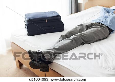 Low section of young businessman sleeping beside suitcase in hotel room View Large Photo Image Stock Image - Low section of young businessman sleeping beside suitcase in hotel room. Fotosearch