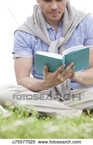 Low section of young man reading book on grass View Large Photo Image Stock Photography - Low section of young man reading book on grass. Fotosearch