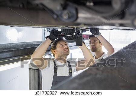 Maintenance engineers repairing car in workshop View Large Photo Image Stock Photo - Maintenance engineers repairing car in workshop. Fotosearch