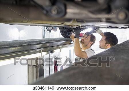 Maintenance engineers repairing car in workshop View Large Photo Image Stock Photo - Maintenance engineers repairing car in workshop. Fotosearch