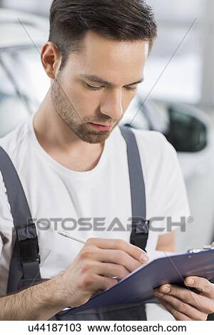 Male automobile mechanic writing on clipboard in workshop View Large Photo Image Stock Image - Male automobile mechanic writing on clipboard in workshop. Fotosearch