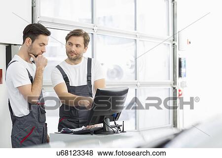 Male automobile mechanics conversing in repair shop View Large Photo Image Stock Photo - Male automobile mechanics conversing in repair shop. Fotosearch
