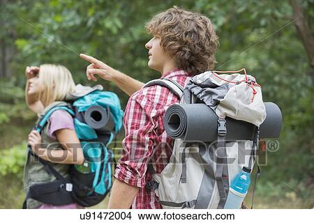Picture - Male backpacker showing something to woman in forest. Fotosearch