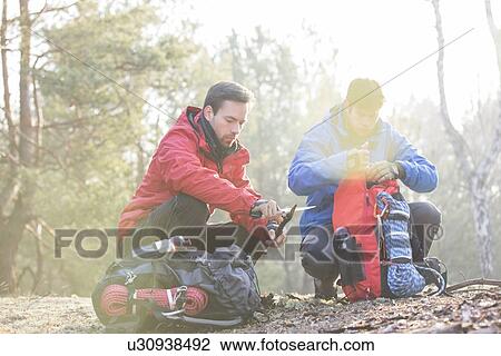 Male backpacker with friend whittling wood in forest View Large Photo Image Stock Image - Male backpacker with friend whittling wood in forest. Fotosearch
