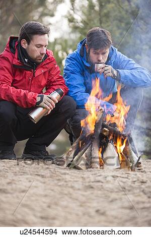 Male backpackers having coffee at campfire in forest View Large Photo Image Picture - Male backpackers having coffee at campfire in forest. Fotosearch