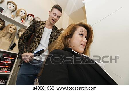 Male hairstylist brushing female customer's hair in salon View Large Photo Image Stock Photo - Male hairstylist brushing female customer's hair in salon. Fotosearch