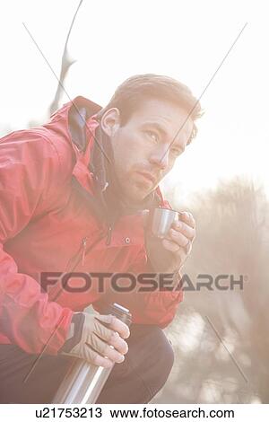 Stock Image - Male hiker having coffee in forest. Fotosearch