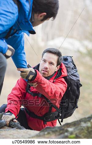 Male hiker helping friend while trekking in forest View Large Photo Image Stock Photograph - Male hiker helping friend while trekking in forest. Fotosearch