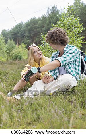 Male hiker pouring coffee for woman while relaxing in field View Large Photo Image Stock Photo - Male hiker pouring coffee for woman while relaxing in field. Fotosearch
