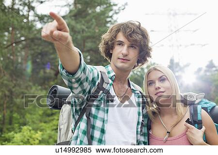 Stock Photography - Male hiker showing something to woman in forest. Fotosearch