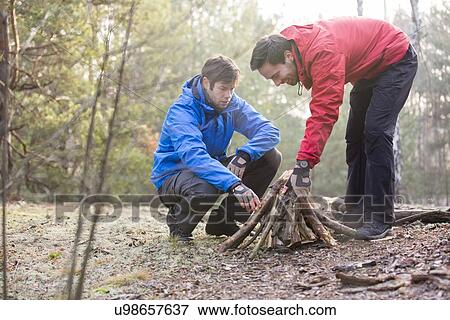 Male hikers arranging firewood in forest View Large Photo Image Stock Photo - Male hikers arranging firewood in forest. Fotosearch