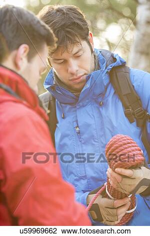 Male hikers looking at rope in forest View Large Photo Image Stock Image - Male hikers looking at rope in forest. Fotosearch