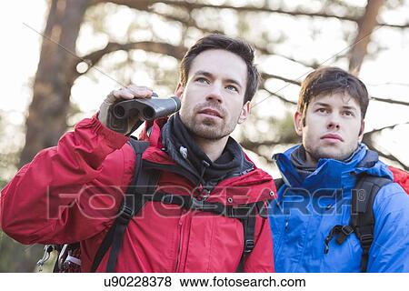 Stock Photo - Male hikers with binoculars in forest. Fotosearch