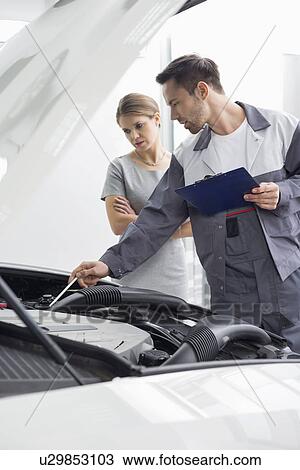 Male maintenance engineer explaining car engine to female customer in repair shop View Large Photo Image Stock Image - Male maintenance engineer explaining car engine to female customer in repair shop. Fotosearch