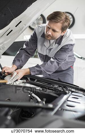 Picture - Male mechanic repairing car engine in workshop. Fotosearch