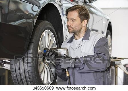 Male mechanic repairing car's wheel in workshop View Large Photo Image Stock Photo - Male mechanic repairing car's wheel in workshop. Fotosearch