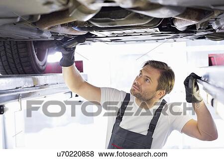 Male repair worker examining car in workshop View Large Photo Image Stock Photo - Male repair worker examining car in workshop. Fotosearch