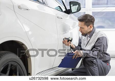 Male repair worker examining car paint with equipment in repair shop View Large Photo Image Stock Photo - Male repair worker examining car paint with equipment in repair shop. Fotosearch