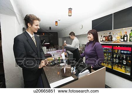 Stock Image - Manager communicating with cashier at bar counter. Fotosearch