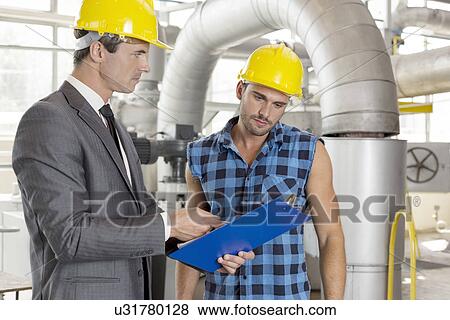 Manager with worker discussing over clipboard in industry View Large Photo Image Stock Photo - Manager with worker discussing over clipboard in industry. Fotosearch