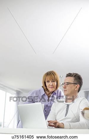 Mature couple using laptop together at home View Large Photo Image Stock Photography - Mature couple using laptop together at home. Fotosearch