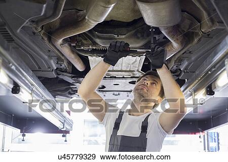Mid adult automobile mechanic repairing car in workshop View Large Photo Image Stock Photo - Mid adult automobile mechanic repairing car in workshop. Fotosearch