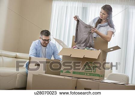 Mid-adult couple unpacking cardboard boxes in new home View Large Photo Image Stock Image - Mid-adult couple unpacking cardboard boxes in new home. Fotosearch