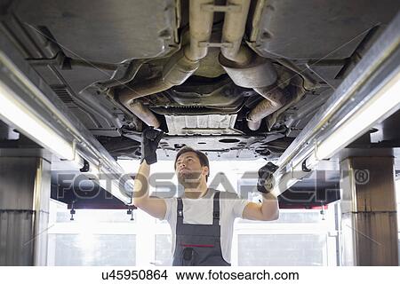 Picture - Mid adult male repair worker repairing car in workshop. Fotosearch