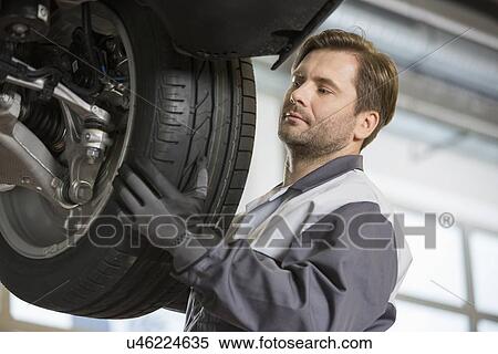 Mid adult technician adjusting car's tire in workshop View Large Photo Image Stock Photography - Mid adult technician adjusting car's tire in workshop. Fotosearch