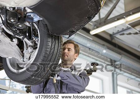 Mid adult technician repairing car's wheel in workshop View Large Photo Image Stock Image - Mid adult technician repairing car's wheel in workshop. Fotosearch