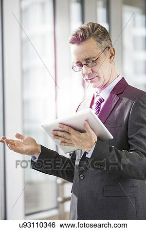 Middle aged businessman using tablet PC in office View Large Photo Image Stock Photograph - Middle aged businessman using tablet PC in office. Fotosearch