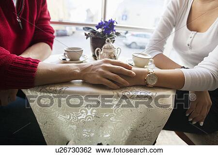 Midsection of couple holding hands in cafe View Large Photo Image Stock Image - Midsection of couple holding hands in cafe. Fotosearch