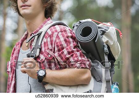 Midsection of male hiker carrying backpack in forest View Large Photo Image Stock Photo - Midsection of male hiker carrying backpack in forest. Fotosearch