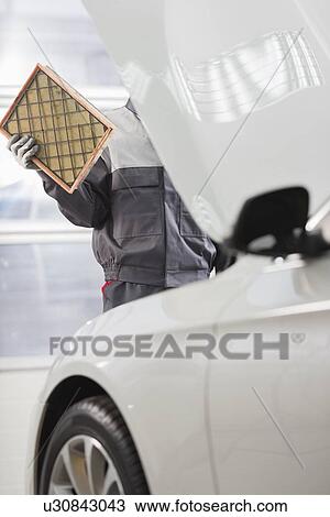 Stock Image - Midsection of male maintenance engineer repairing car in automobile store. Fotosearch