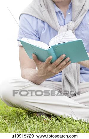 Stock Photo - Midsection of man holding book in park. Fotosearch
