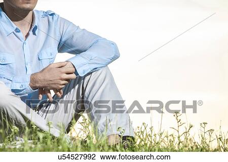 Midsection of man sitting on grass against clear sky View Large Photo Image Stock Image - Midsection of man sitting on grass against clear sky. Fotosearch