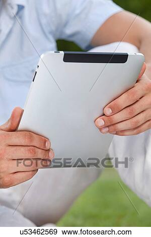 Stock Photo - Midsection of man using digital tablet in park. Fotosearch