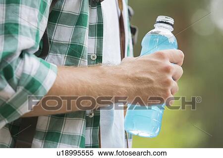 Stock Photography - Midsection of man with energy drink outdoors. Fotosearch