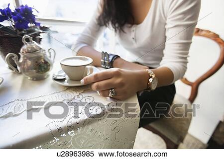 Stock Photography - Midsection of woman having coffee at cafe. Fotosearch