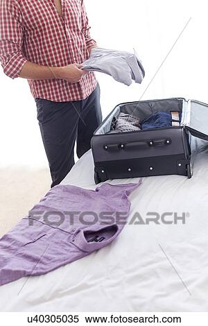 Midsection of young businessman unpacking luggage in hotel room View Large Photo Image Stock Photography - Midsection of young businessman unpacking luggage in hotel room. Fotosearch