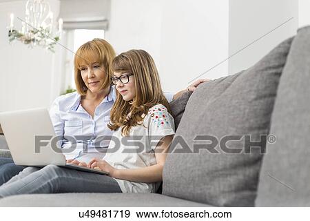 Stock Photo - Mother and daughter using laptop together at home. Fotosearch