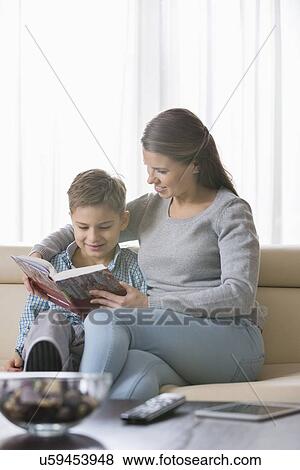 Stock Photo - Mother and son reading book on sofa at home. Fotosearch