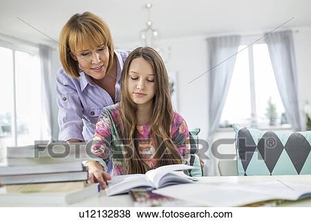 Mother assisting daughter in doing homework at table View Large Photo Image Stock Photo - Mother assisting daughter in doing homework at table. Fotosearch