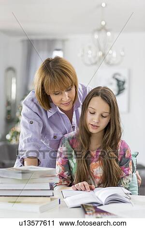 Mother guiding daughter in doing homework at table View Large Photo Image Stock Image - Mother guiding daughter in doing homework at table. Fotosearch