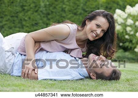 Playful young couple having leisure time in park View Large Photo Image Stock Image - Playful young couple having leisure time in park. Fotosearch