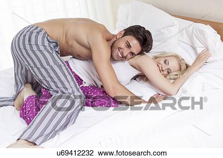 Playful young couple in bed View Large Photo Image Stock Image - Playful young couple in bed. Fotosearch