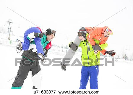 Stock Photo - Playful young couples enjoying in snow. Fotosearch