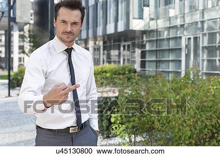 Portrait of angry businessman showing middle finger outside office building View Large Photo Image Stock Image - Portrait of angry businessman showing middle finger outside office building. Fotosearch